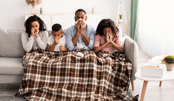 a family sitting on a couch with a blanket covering their mouth